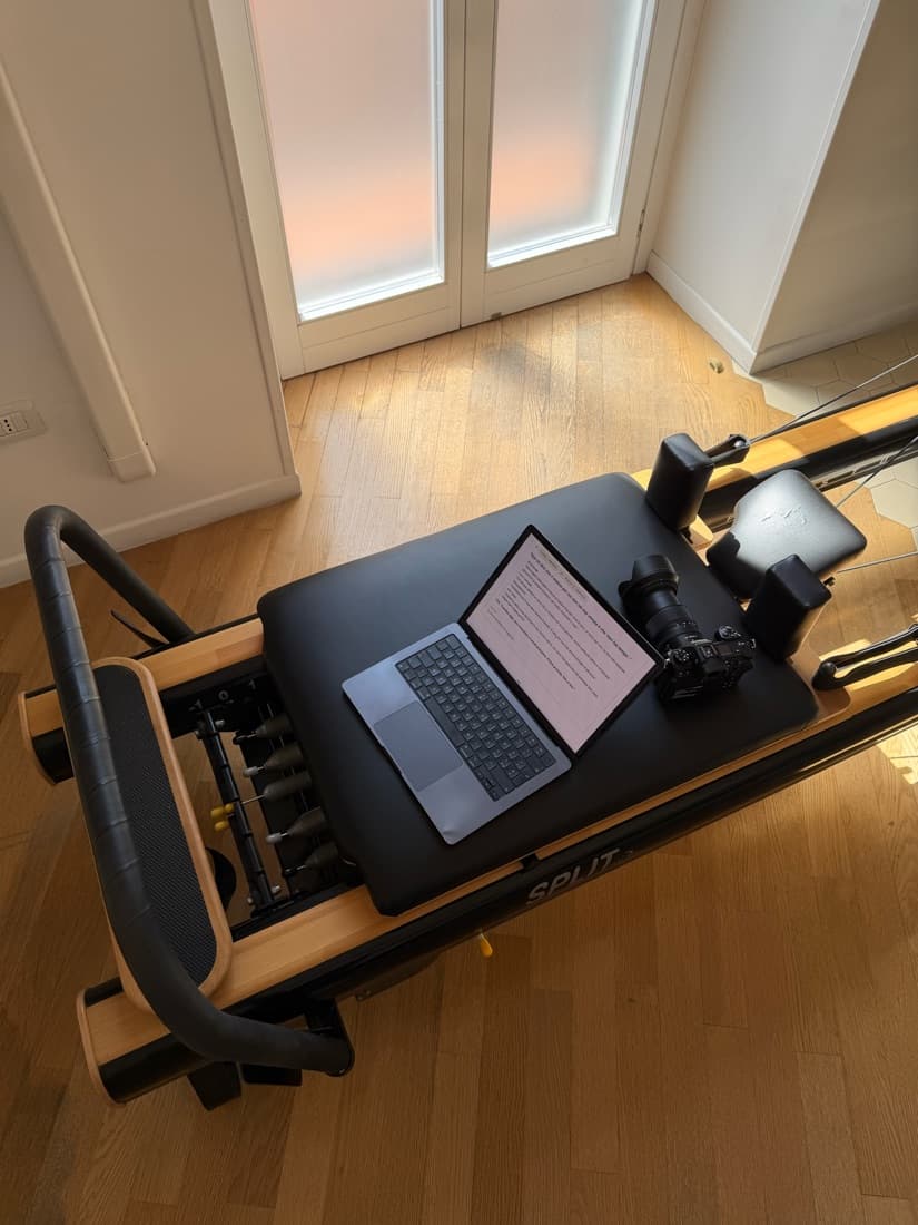 Un portatile aperto sul testo di un video, accanto a una fotocamera, su una macchina da pilates